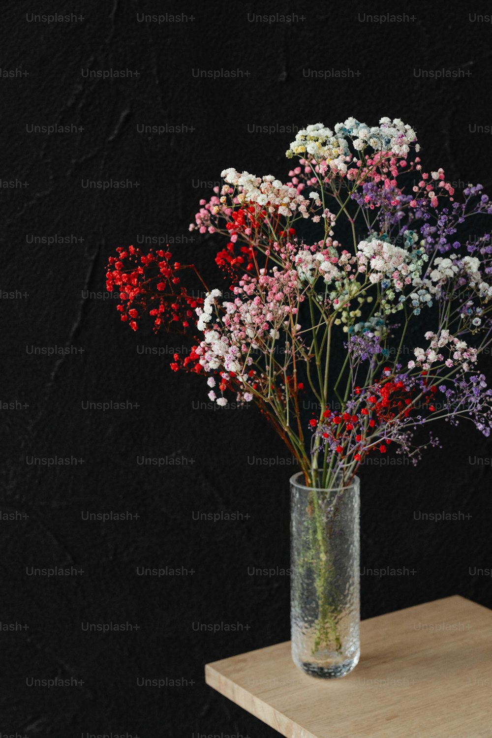 um vaso cheio de flores sentado em cima de uma mesa de madeira