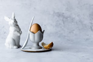 a white bunny and a broken egg on a plate