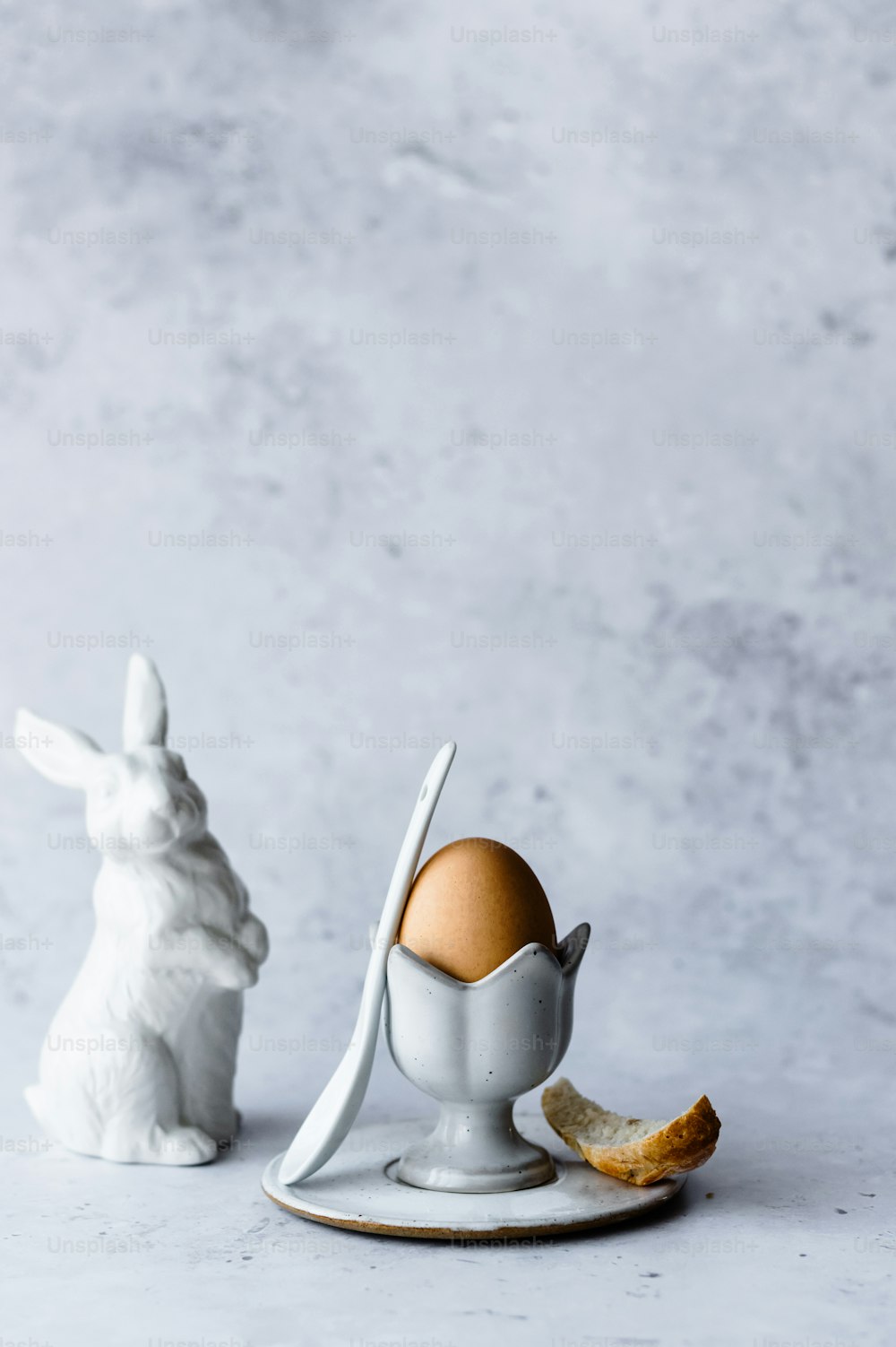 Una statuetta di coniglio bianco accanto a un uovo rotto
