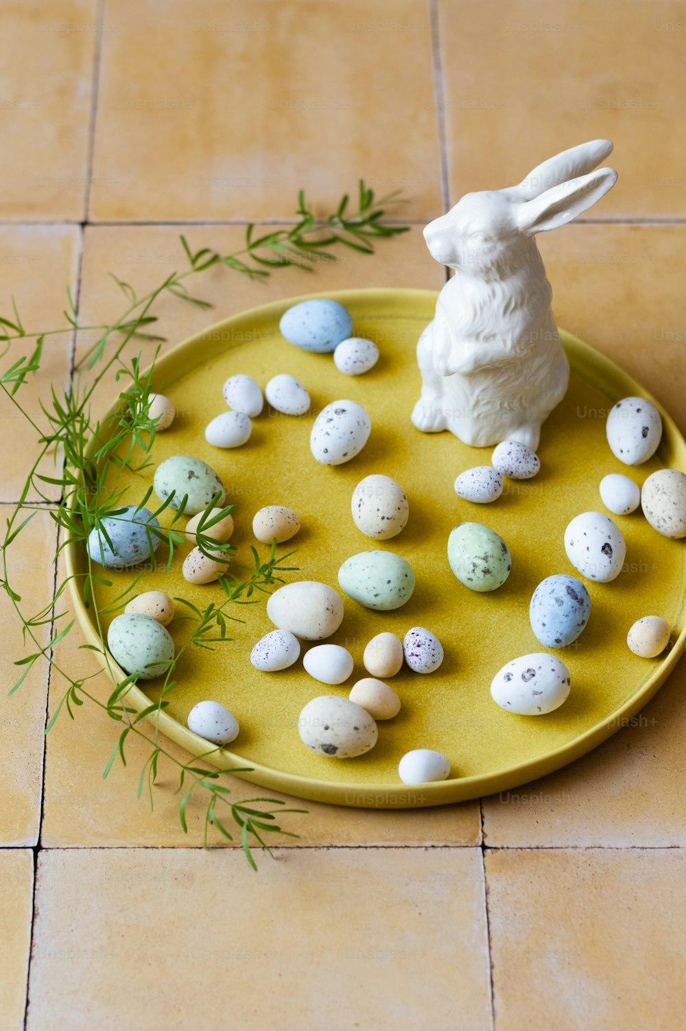 un plato amarillo cubierto con pequeños huevos y una estatua de conejito