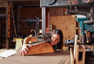 a woman is making a piece of wood