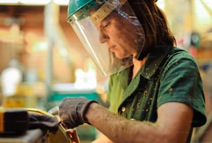 a woman wearing a protective helmet working on a piece of equipment