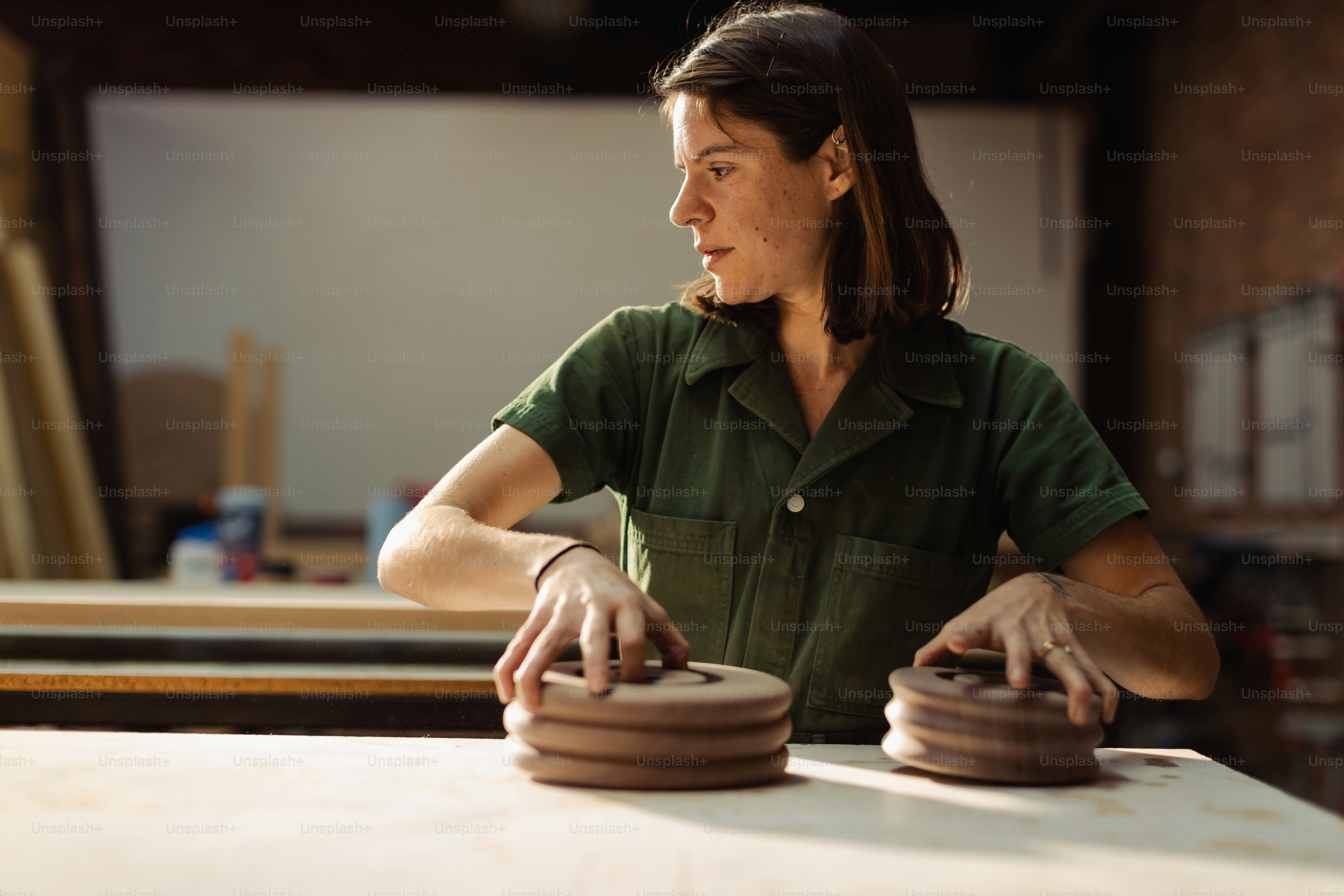 a woman in a green shirt working on a piece of wood