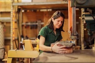 Una mujer con una camisa verde trabajando en un pedazo de madera