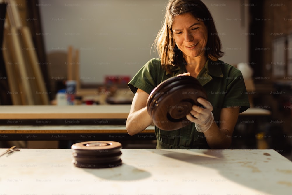 a woman in a green shirt working on a piece of wood