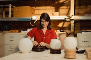 a woman in a red shirt working on some lamps