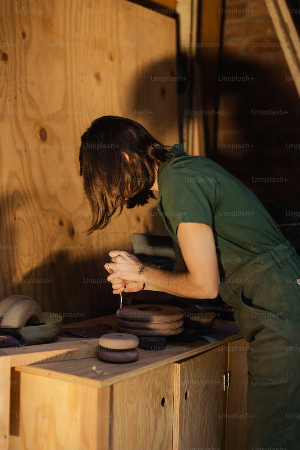 a woman in a green apron working on a piece of pottery