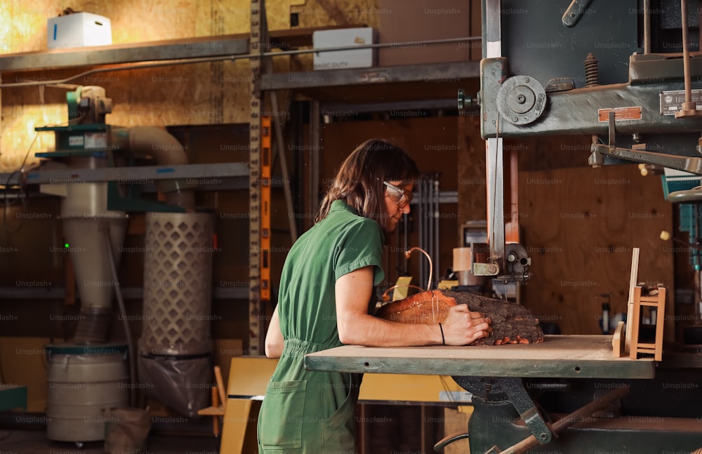 a woman in a green shirt working on a piece of wood