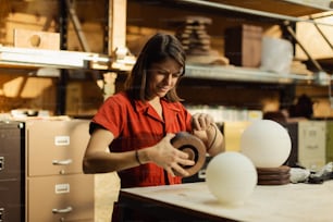 a woman in a red shirt working on a sculpture