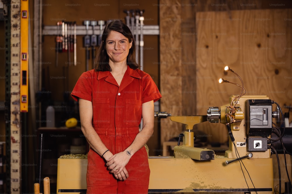a woman in a red jumpsuit standing in front of a machine