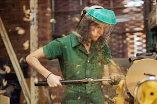 um homem de camisa verde e um capacete verde trabalhando em uma máquina