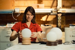 a woman in a red shirt working on a light fixture