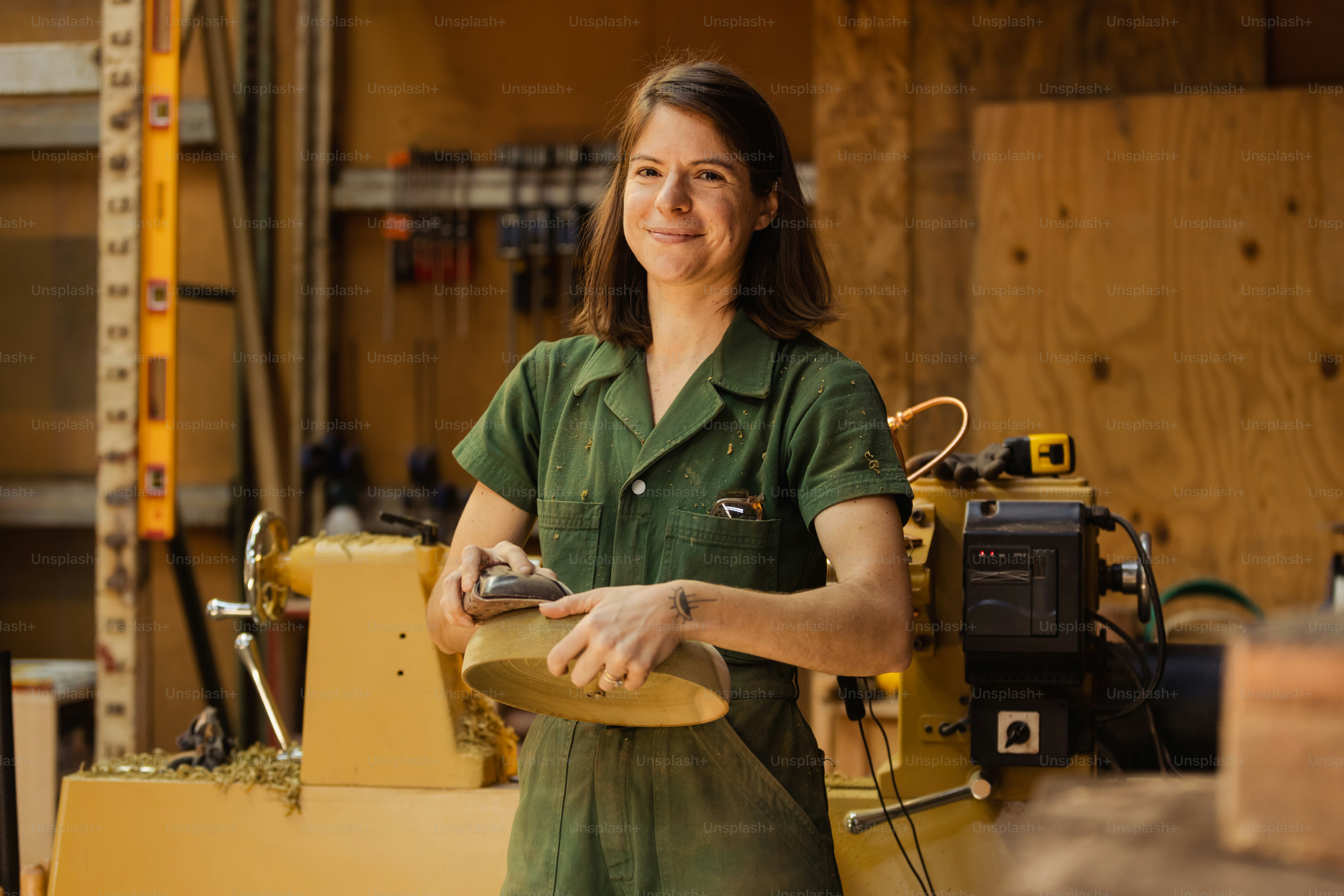 Eine Frau im grünen Hemd arbeitet an einem Stück Holz