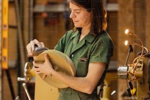 Una mujer con una camisa verde trabajando en un pedazo de madera