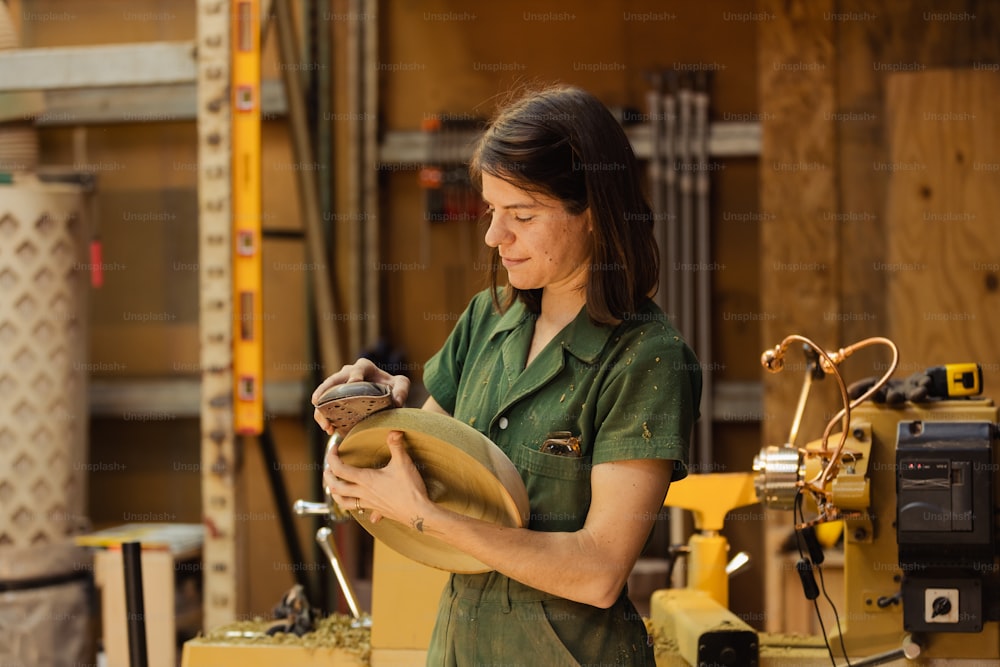 Eine Frau im grünen Hemd arbeitet an einem Stück Holz