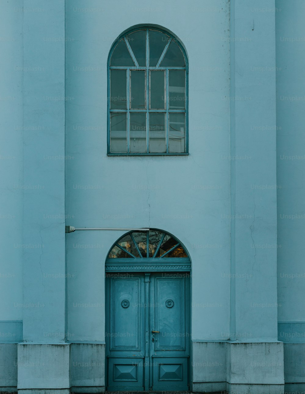 Un edificio con una puerta azul y una ventana arqueada