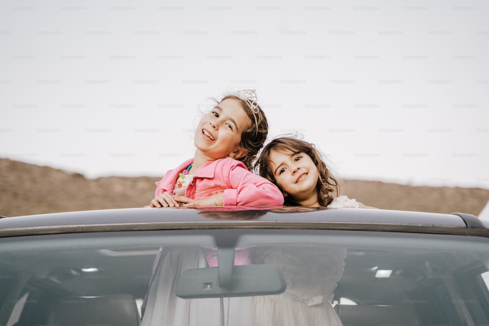 a couple of girls that are sitting in the back of a car