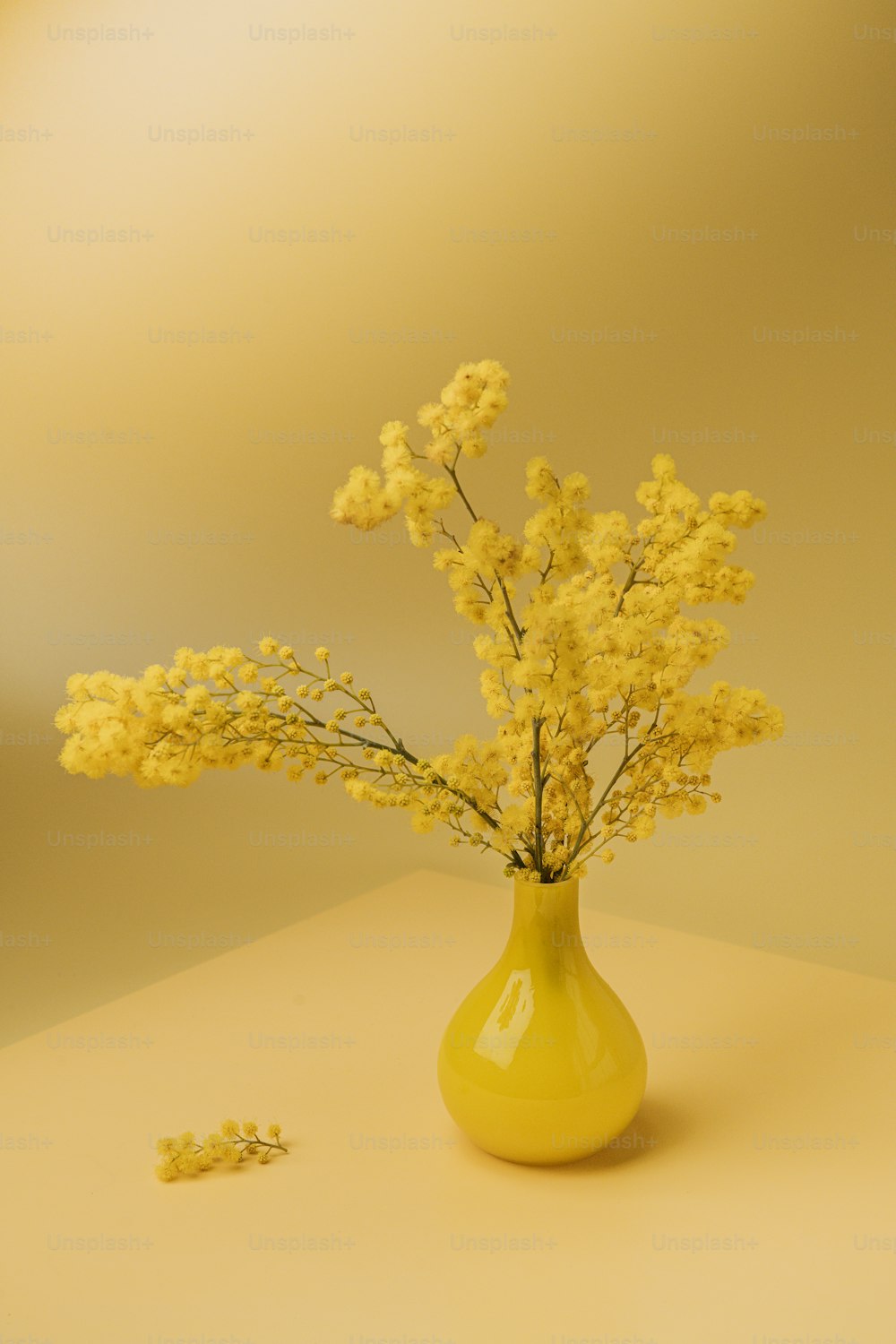 eine gelbe Vase gefüllt mit gelben Blumen auf einem Tisch