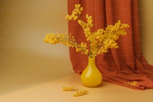 um vaso amarelo cheio de flores amarelas ao lado de uma cortina vermelha
