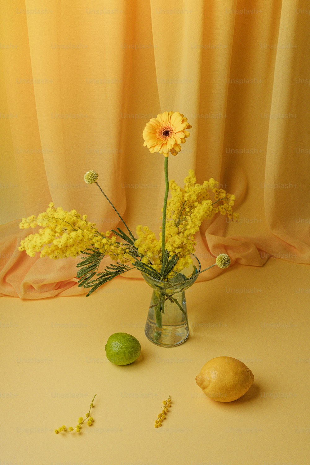 a vase with flowers and lemons on a table