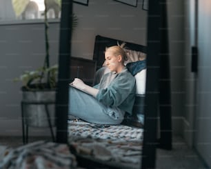a woman sitting on a bed looking at her laptop