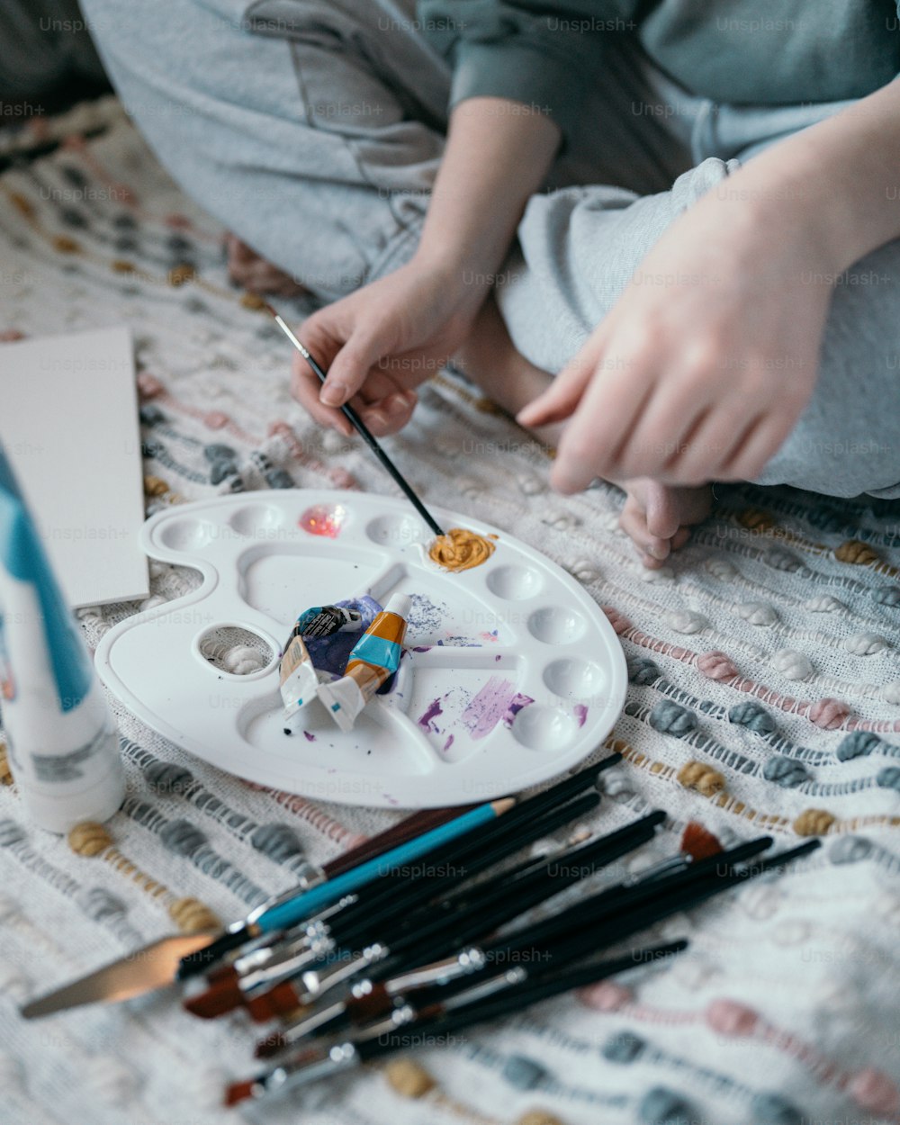 Un enfant peint sur une assiette avec des pinceaux