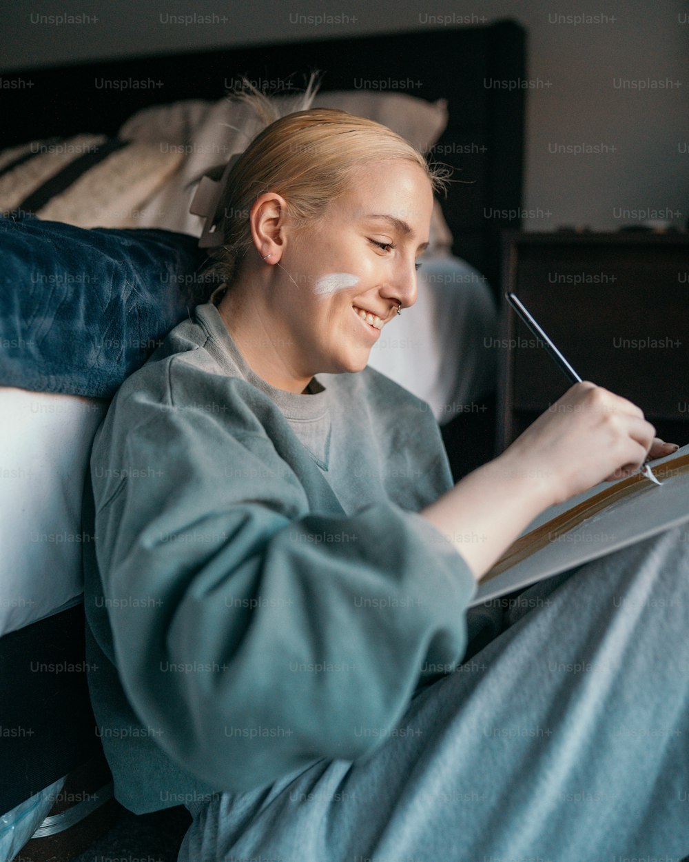 Une femme assise sur un lit écrivant sur un morceau de papier