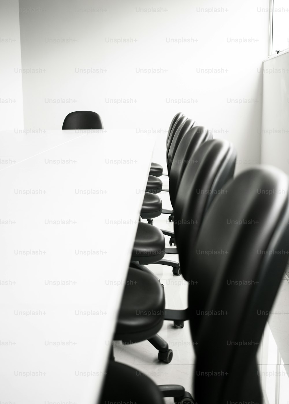 a row of black chairs sitting next to a white table