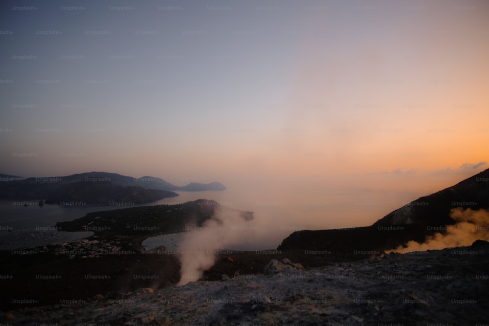 steam rises from the ground near a body of water