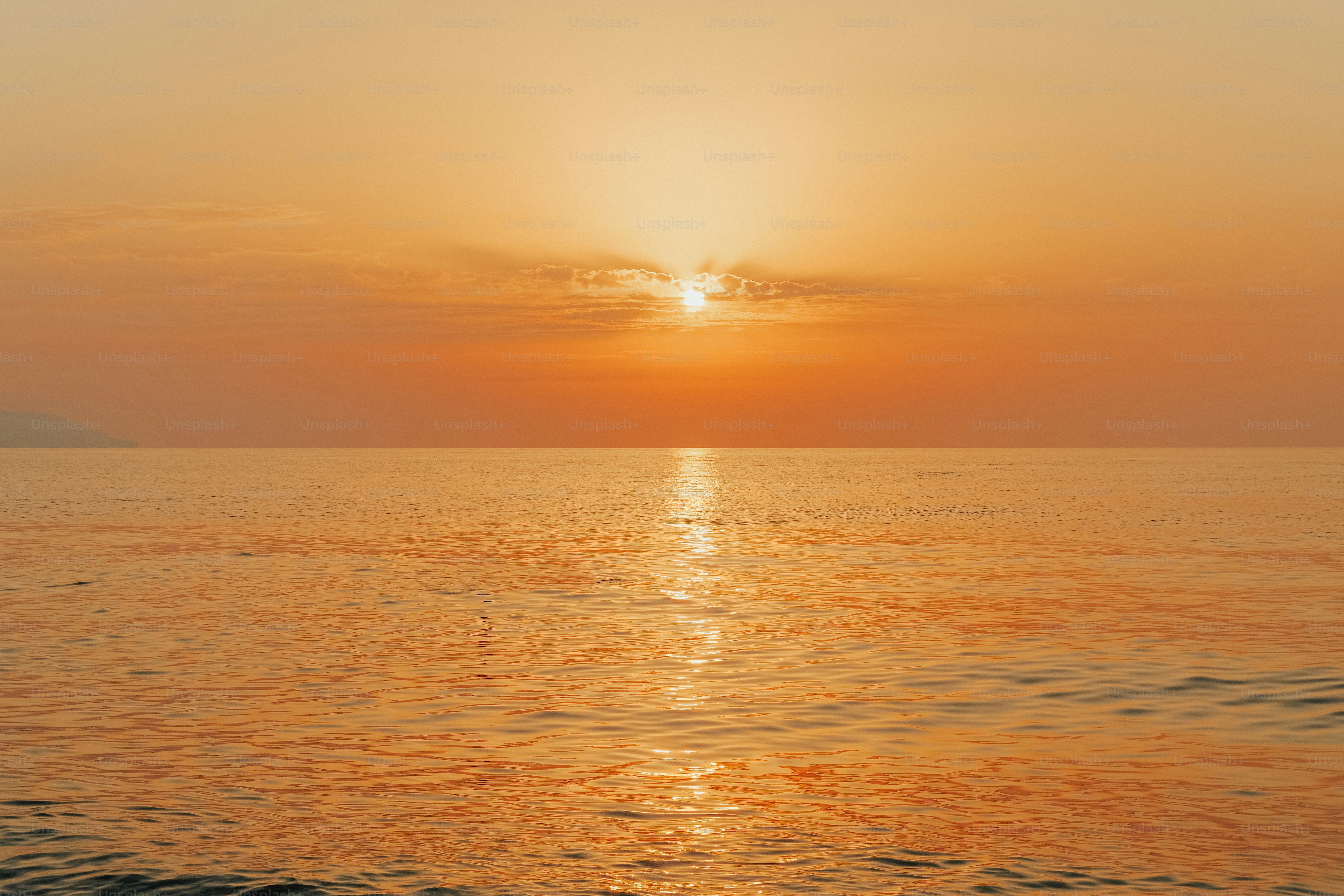 a large body of water with a sunset in the background