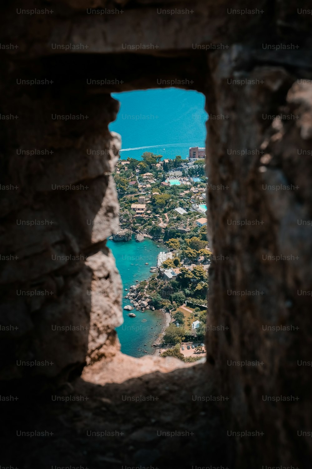 a view of a lake through a hole in a stone wall