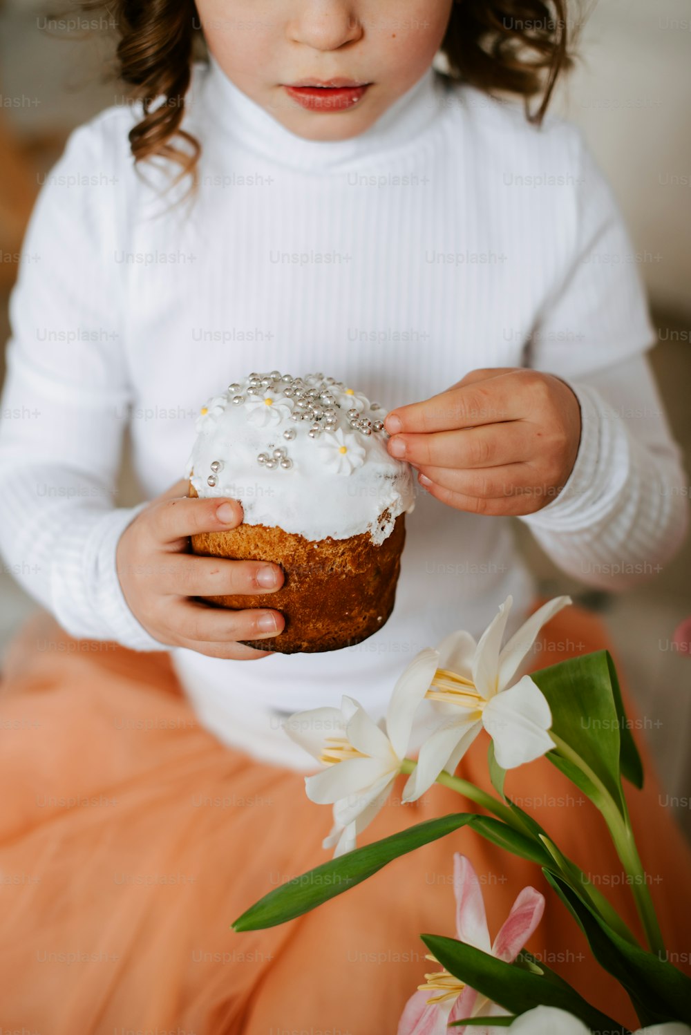 a little girl holding a frosted cupcake in her hands