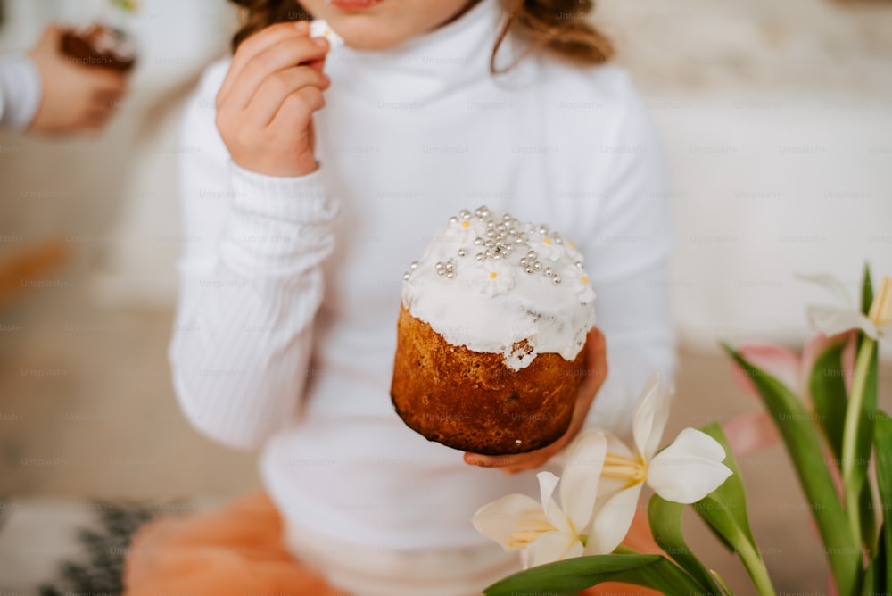 a little girl holding a frosted cupcake in her hand