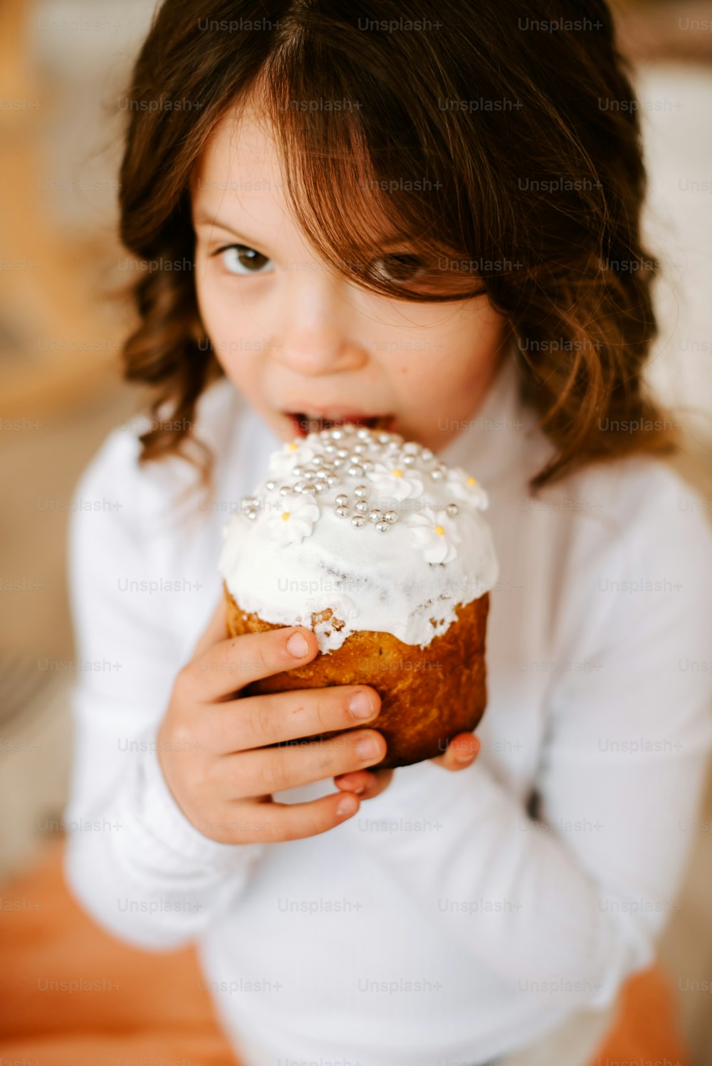 a little girl eating a frosted donut