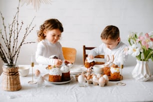 a couple of kids sitting at a table with food