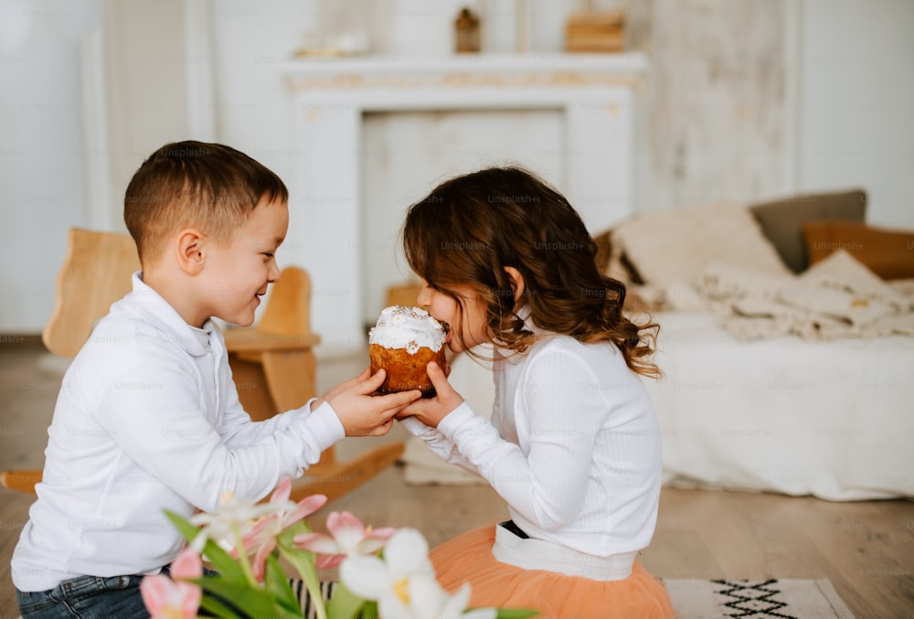 Un ragazzo e una ragazza seduti sul pavimento che mangiano cupcakes