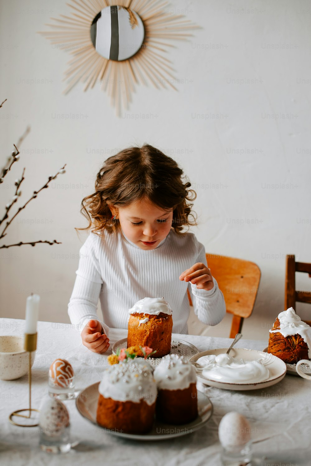 a little girl sitting at a table with a cake