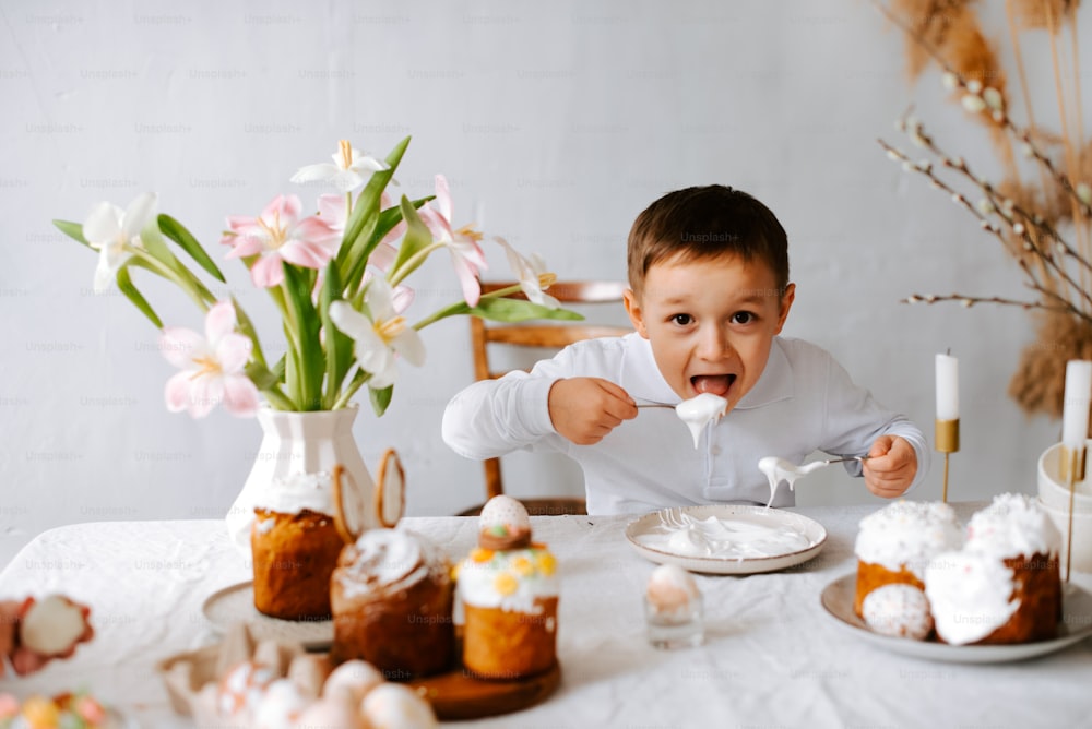 a little boy sitting at a table eating cake