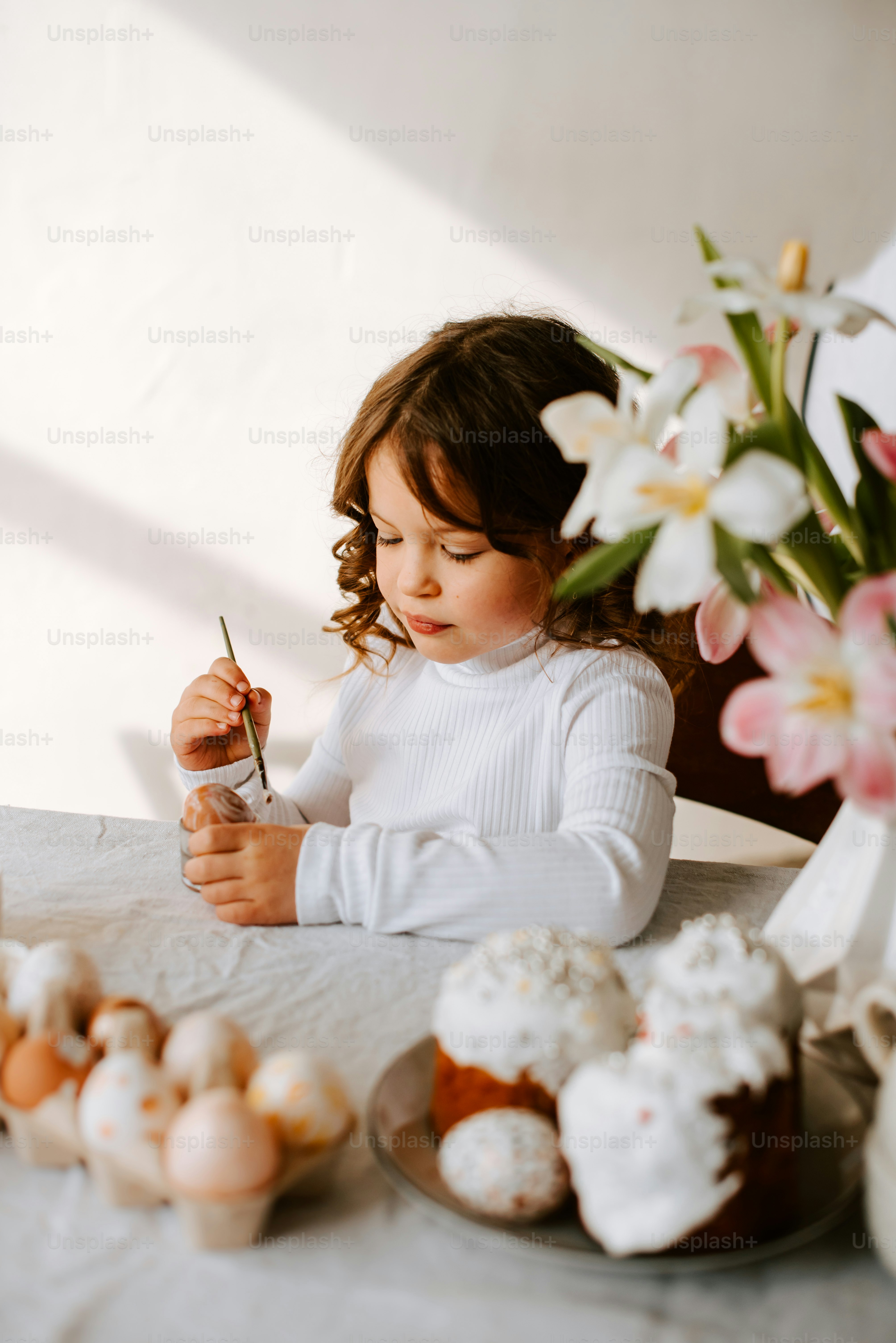 a little girl sitting at a table with some food