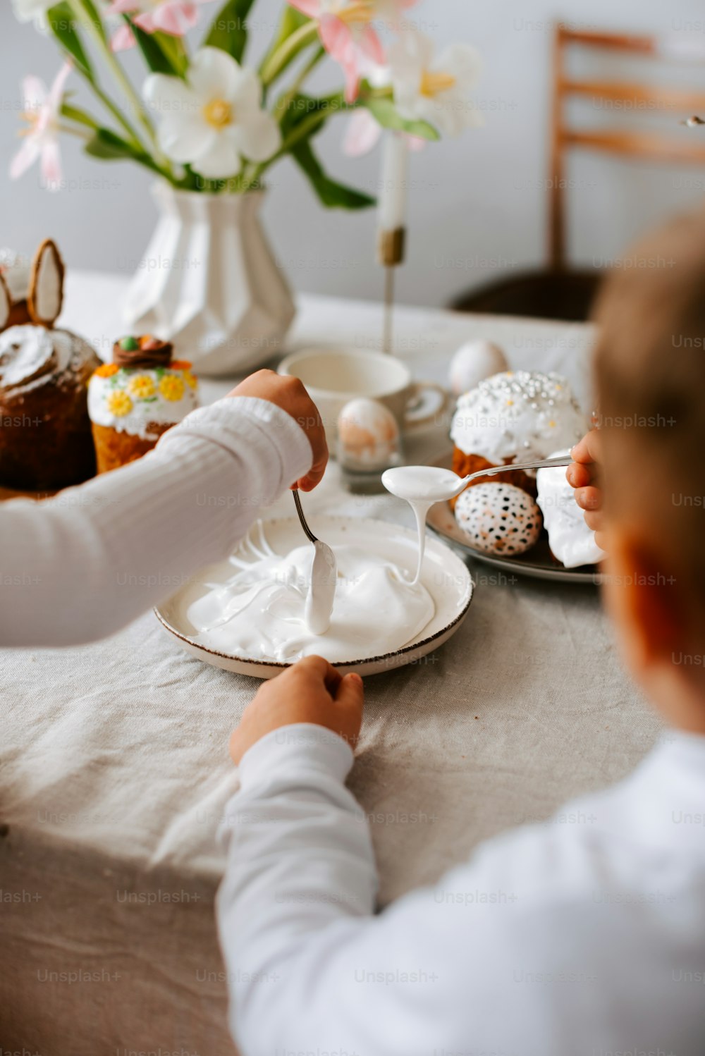 a little boy sitting at a table with a plate of food