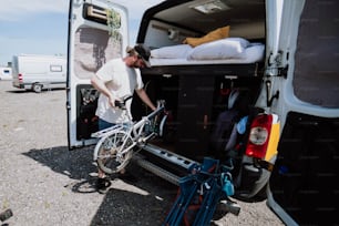 um homem carregando sua bicicleta na parte de trás de uma van
