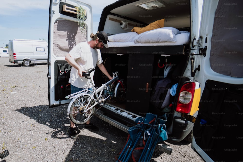um homem carregando sua bicicleta na parte de trás de uma van