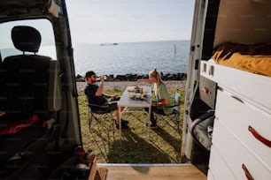 a man and woman sitting at a table in the back of a van