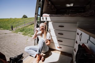 Eine Frau sitzt auf der Ladefläche eines Lastwagens und trinkt aus einer Flasche