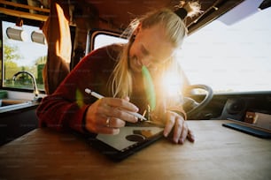a woman sitting at a table writing on a tablet
