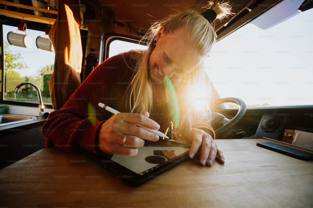 uma mulher sentada em uma mesa escrevendo em um tablet