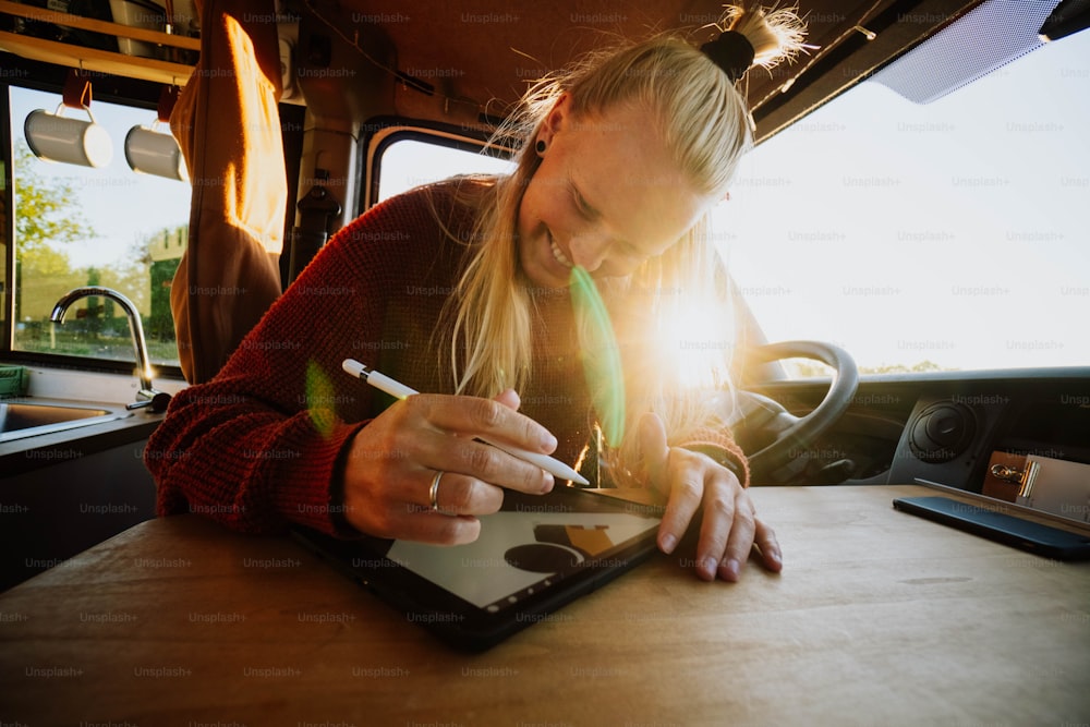 a woman sitting at a table writing on a tablet