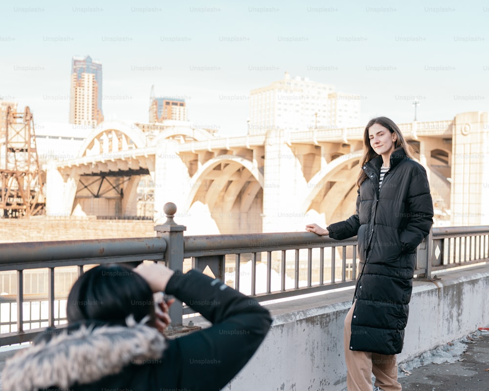 a woman taking a picture of another woman on a bridge