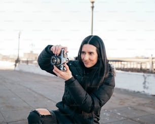 Una donna seduta a terra con in mano una macchina fotografica