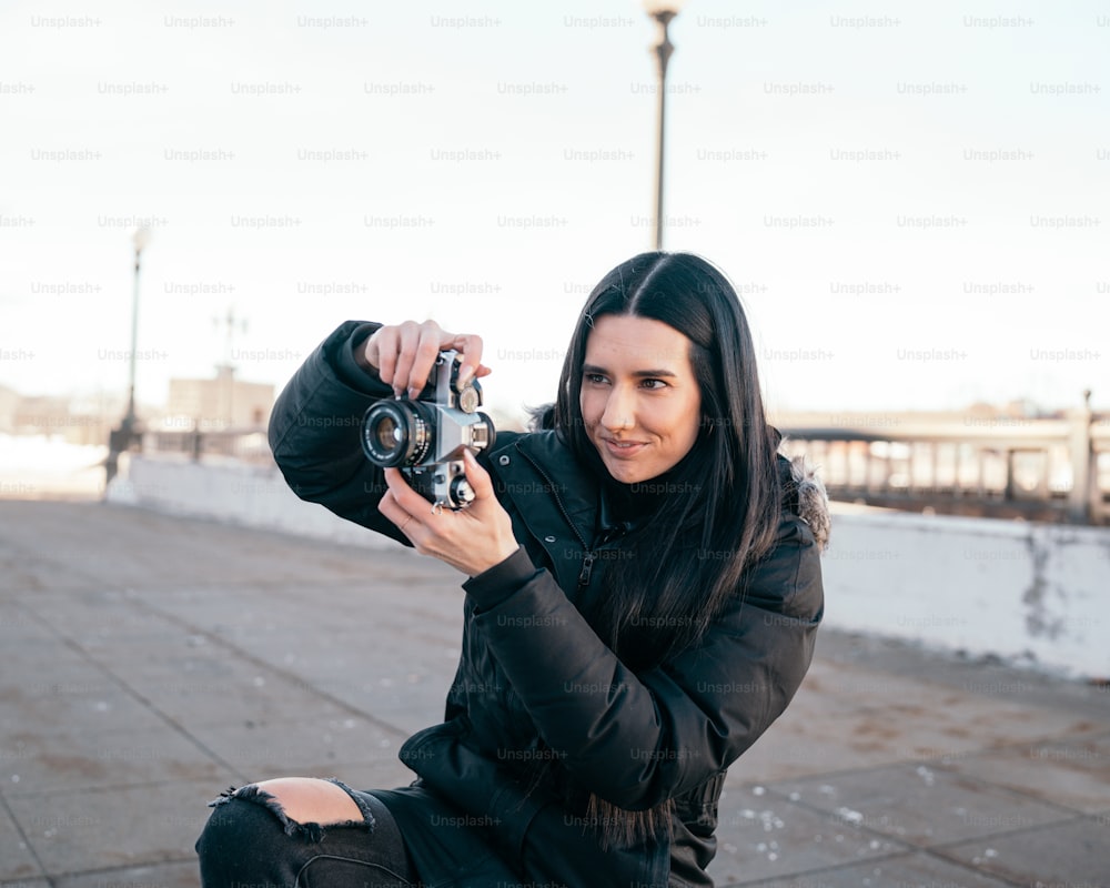 a woman sitting on the ground holding a camera